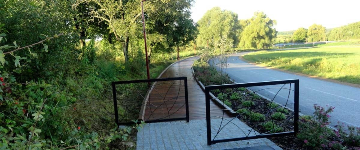 Le cheminement piéton aménagé le long de la route, bordé de verdure